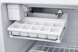 Empty clear plastic ice tray inside a freezer compartment with no ice cubes present, photorealistic view
