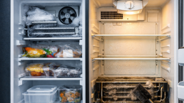open refrigerator door showing cold freezer compartment with frost and warm fridge section with food inside