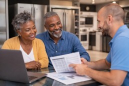 Multicultural family shopping for modern appliances in a bright showroom with a sales associate assisting an older Black