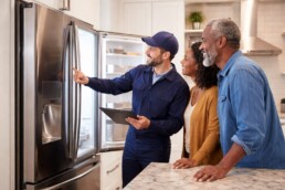 Homeowner and appliance technician discussing repair in a modern kitchen with stainless steel appliances