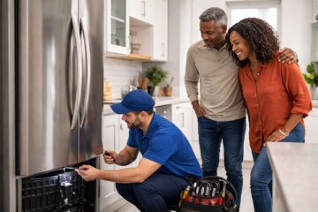 couple examining modern kitchen appliances in showroom with sales associate assisting them