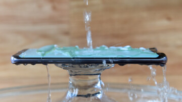 Testing waterproof mobile phone with pouring water splash over water resistant screen
